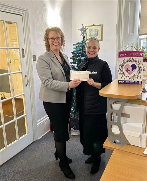 Charity donation presentation at Adams Harrison office, highlighting community support and local engagement.